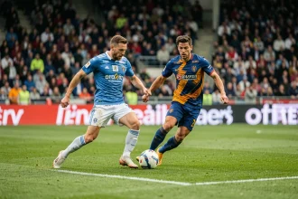 Match de football en direct avec deux joueurs en duel sur la pelouse lors d'un match du FCN